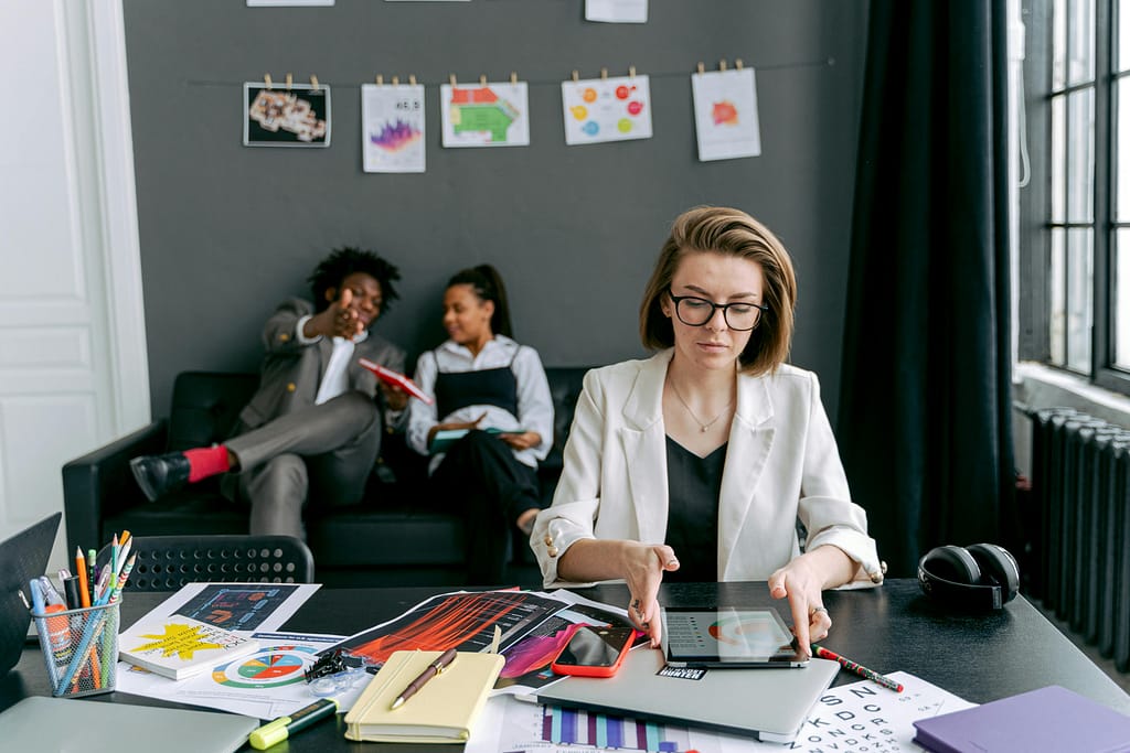 A diverse group working together in a modern office setting with tablets and art on the walls.