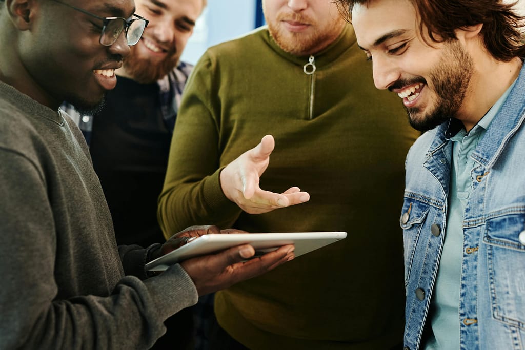 Multicultural team engaged in a discussion, collaborating around a tablet indoors.