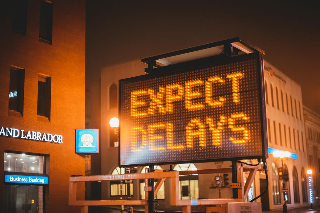 Starting Over When You Feel Delayed Mobile electronic traffic sign with inscription Expect delays placed on road in city street in evening time