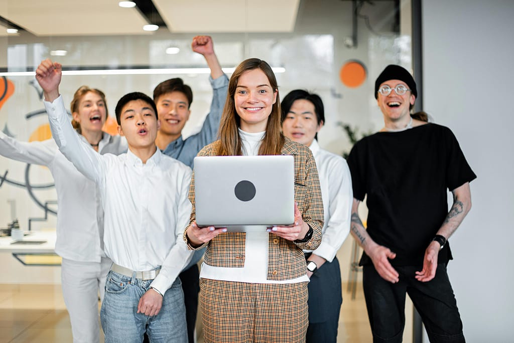 A cheerful, diverse team celebrates success in a modern office environment.