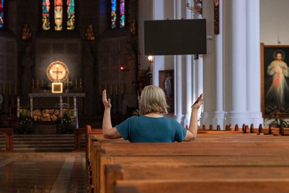 A woman praying with rosary in a Catholic church in Warsaw, Poland, facing the altar.