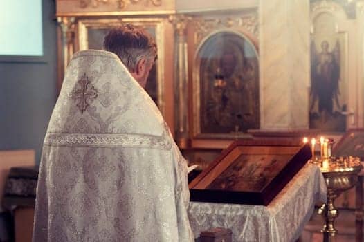 A Catholic priest leads a ceremony in a beautifully adorned chapel with icons and candles.